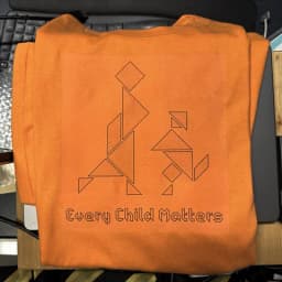 Orange shirt printed with tangram-style figures and the words Every Child Matters.