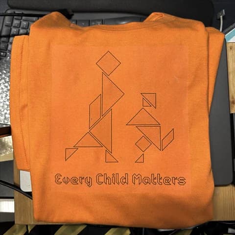 Orange shirt printed with tangram-style figures and the words Every Child Matters.