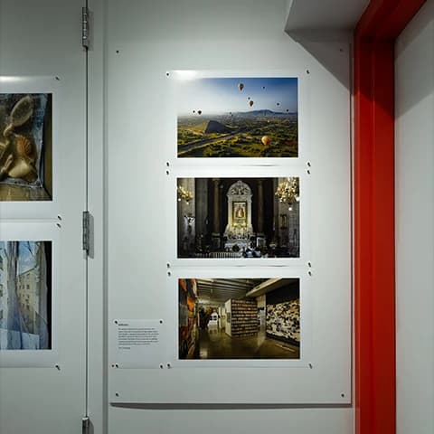 Gallery board with pinned landscape photographs of pyramids, a cathedral altar, and a museum interior.