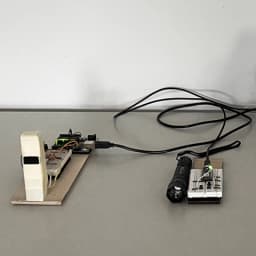 Arduino and breadboard prototype with a white sensor tower, green LED module, and flashlight.